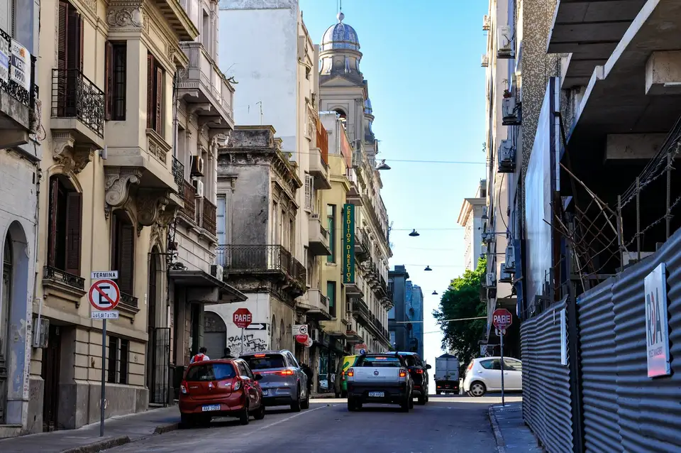 Calle angosta de una ciudad latinoamericana con autos estacionados a ambos lados y edificios antiguos